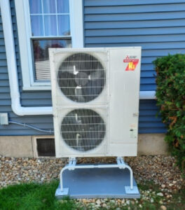 Heat Pump installed outside a house with blue sideing